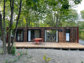 Container im Harz von außen. Terrasse, roter Tisch, rote Stühle.