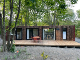Container im Harz von außen. Terrasse, roter Tisch, rote Stühle.